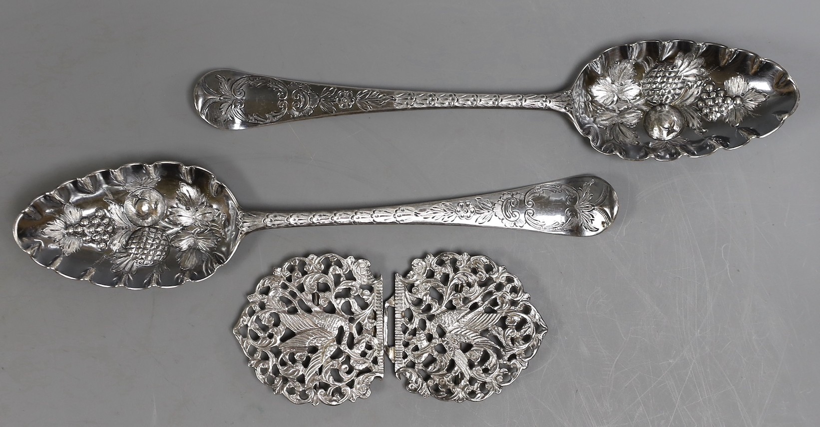 A pair of George III silver Hanovarian pattern 'berry' spoons, Jacob Marsh?, London, 1768, 20.5cm, together with an Edwardian pierced silver nurses buckle, Chester, 1907, decorated with herons, width 10.5cm.